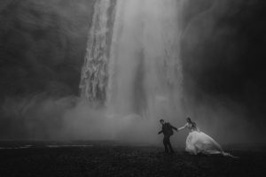 Home Updated 34 wedding and elopement photographer erin and matt getting completely soaked during their skógafoss elopement photos.